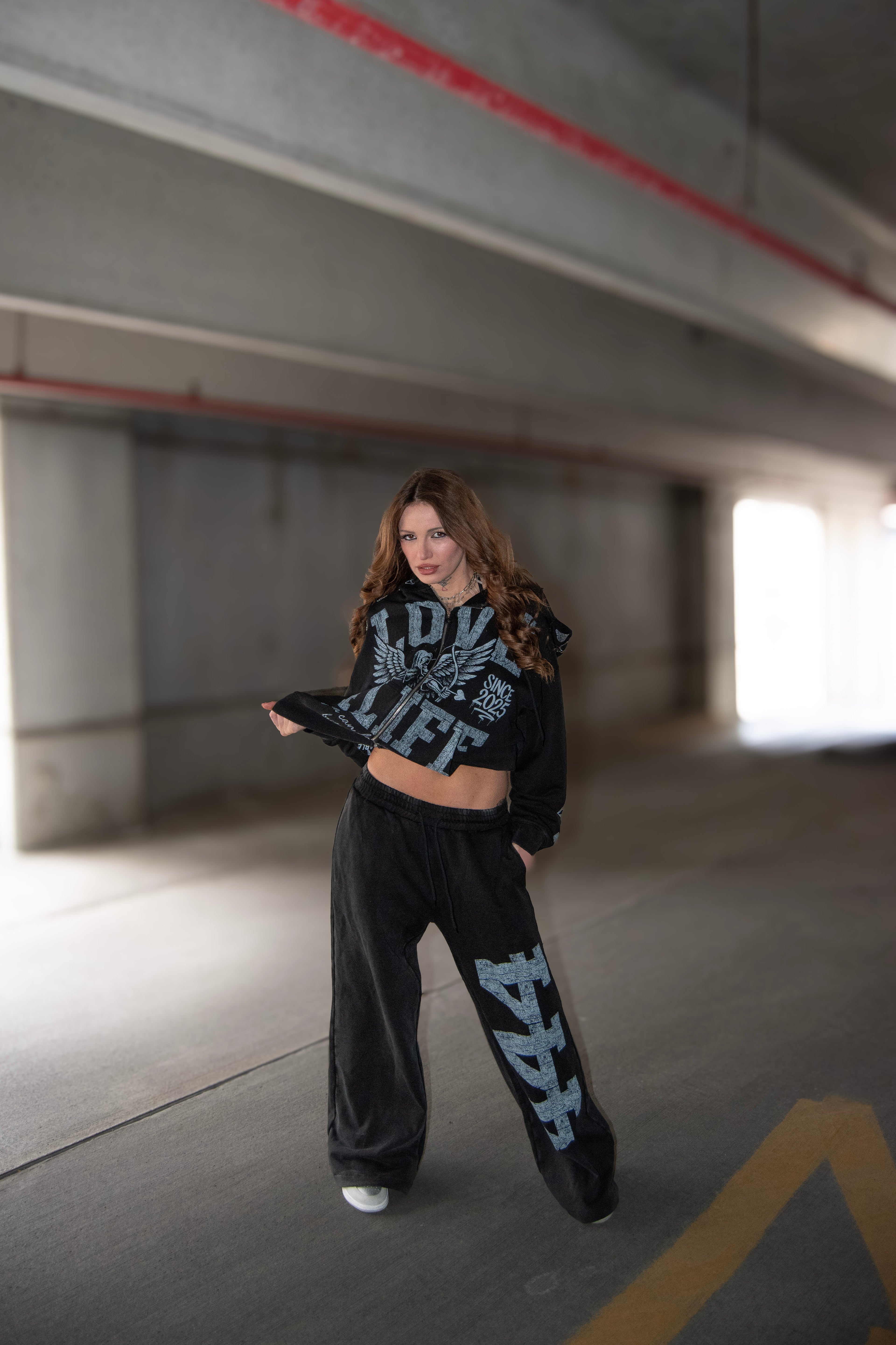 Person wearing a black and white sweatsuit standing in an underpass.